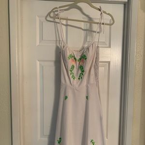 White dress with tie straps and embroidered flowers.